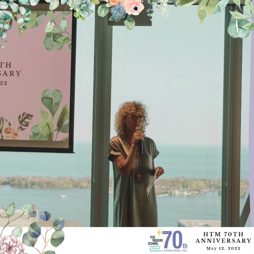 A woman is holding a microphone and speaking at HTM's 70th anniversary event.